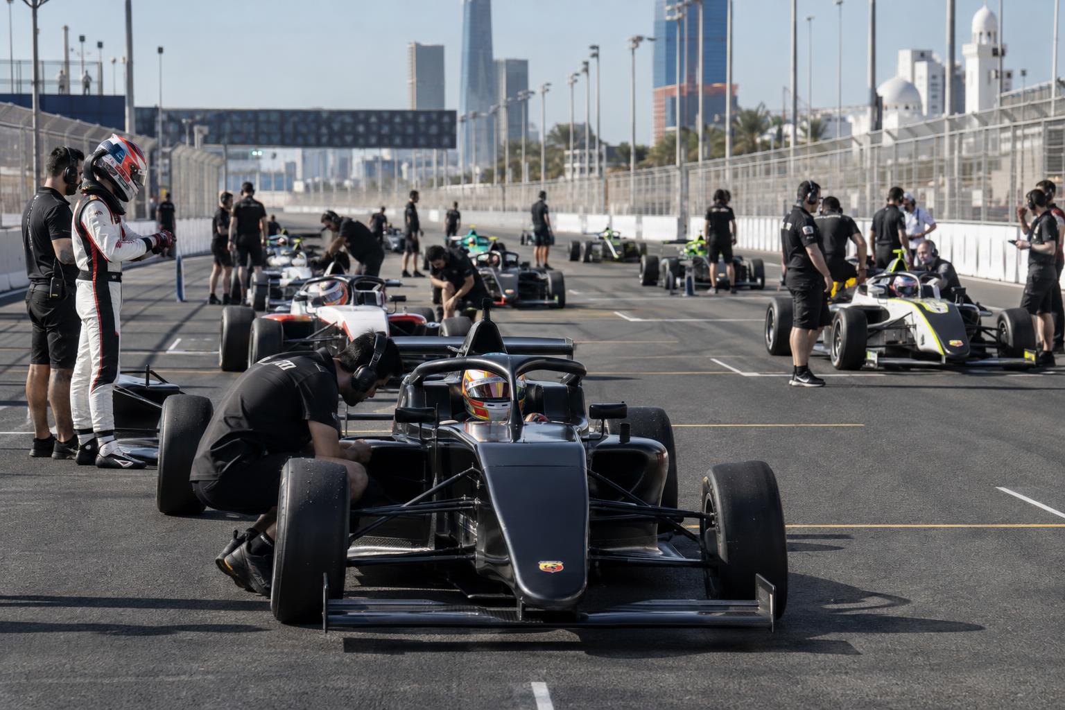 Formula 4 cars and crews prepare on the starting grid at Jeddah Corniche Circuit.
