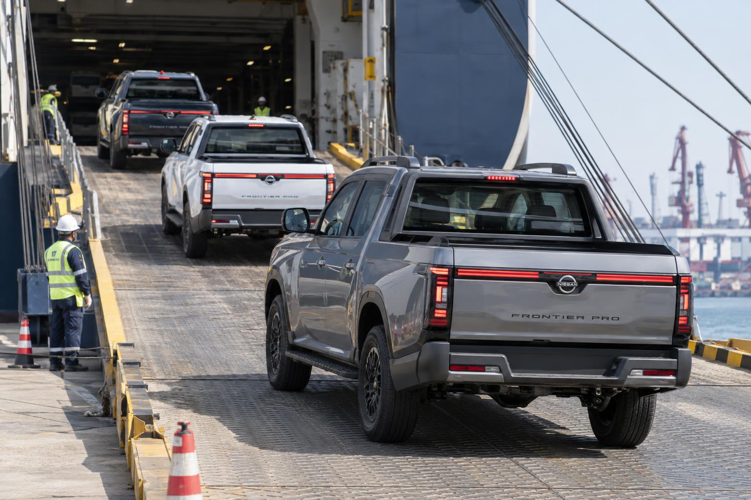 Nissan Frontier Pro pickups loading onto a vehicle carrier at a Chinese export terminal.