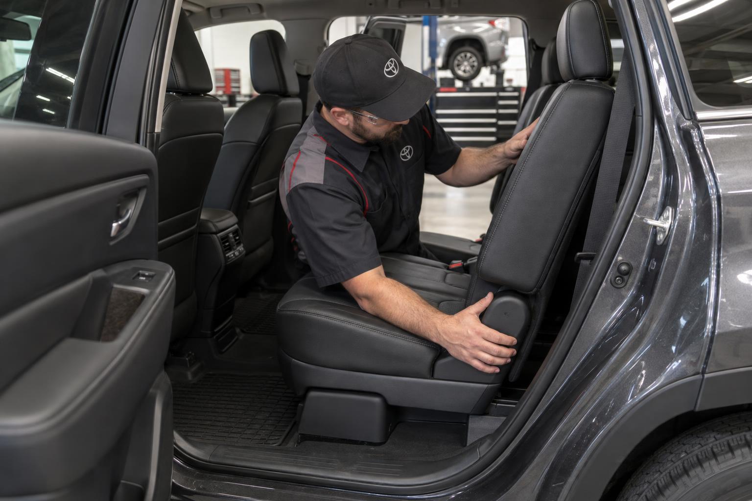 Technician inspecting the second-row seatback area inside a Toyota Highlander.