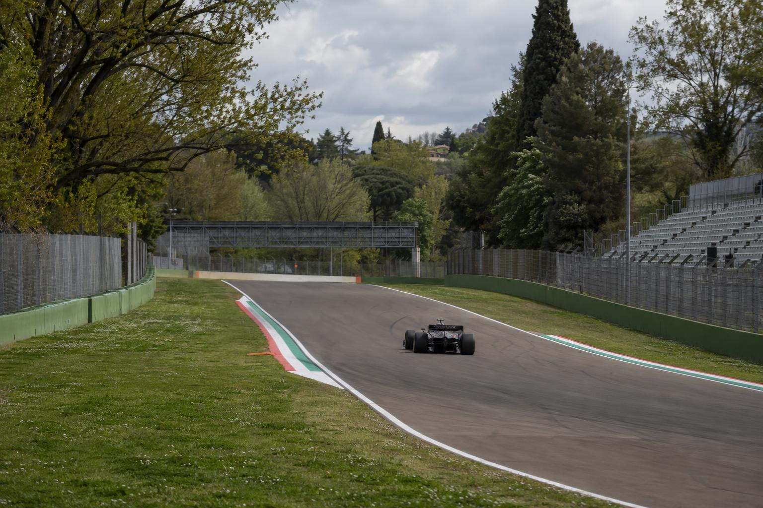 A Formula 1 car on track at the tree-lined Imola circuit in Italy.
