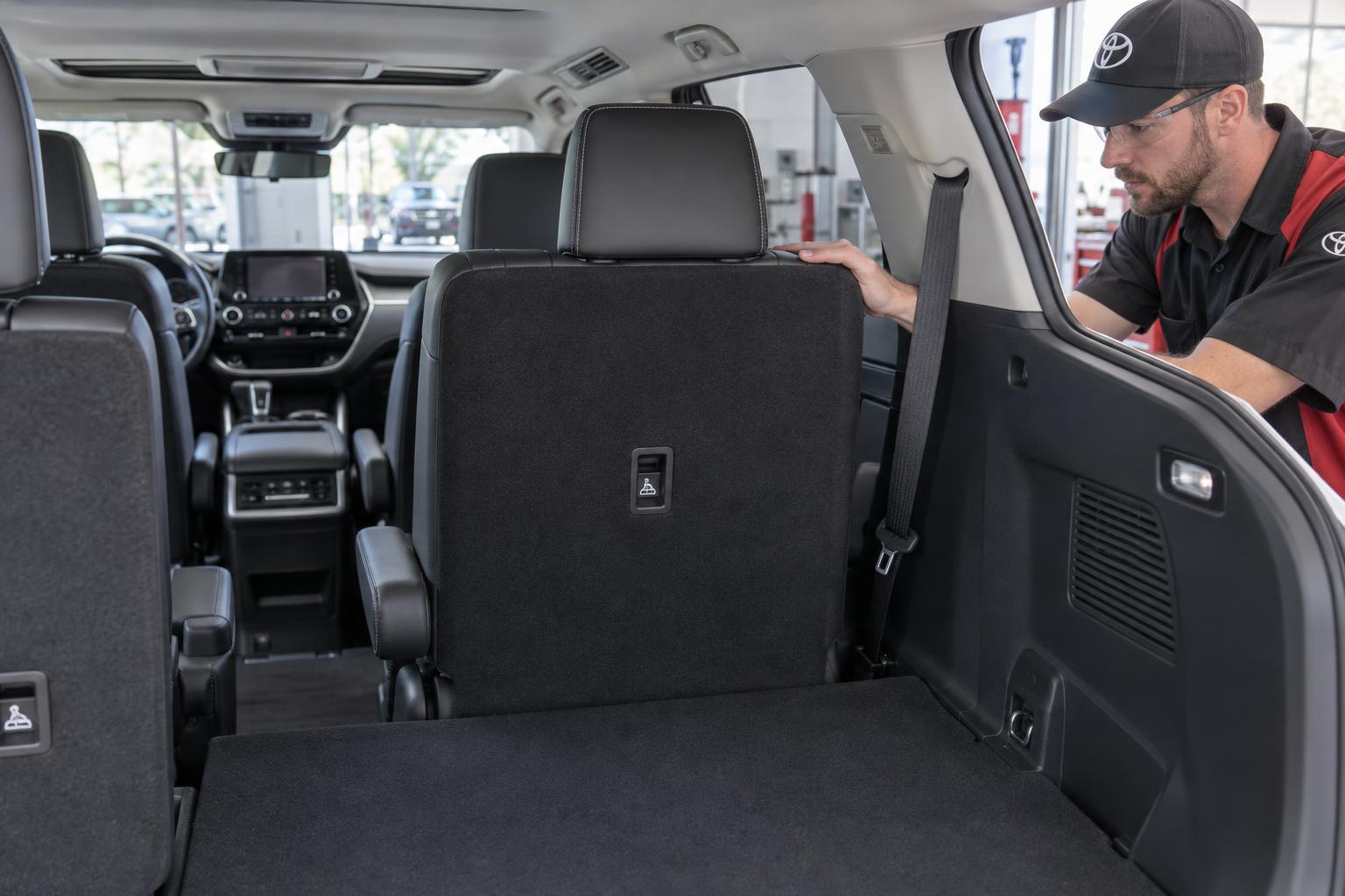 A technician checks that a Toyota Highlander second-row seatback is locked upright.
