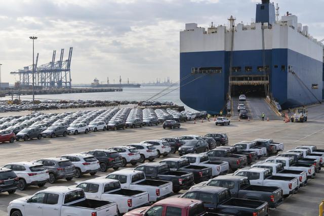 Rows of export vehicles and a car carrier at a Chinese port.