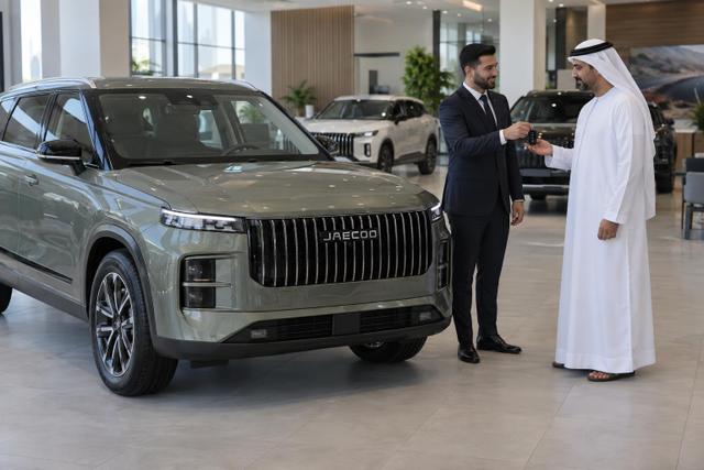 A customer receives a key beside a JAECOO J7 in an Abu Dhabi showroom.