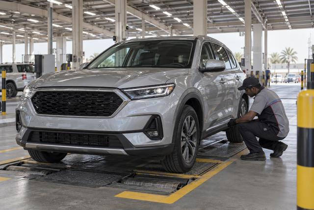 A technician inspects an SUV in a covered vehicle testing lane.