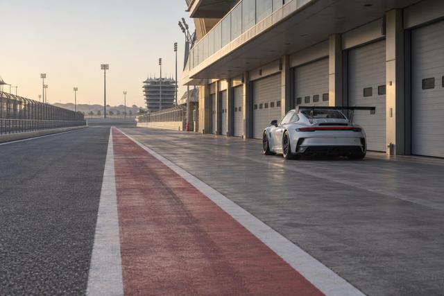 An empty Bahrain circuit pit lane with a Porsche Cup car parked in the distance.