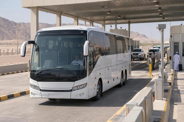 An intercity coach approaching an orderly Gulf land-border inspection lane.