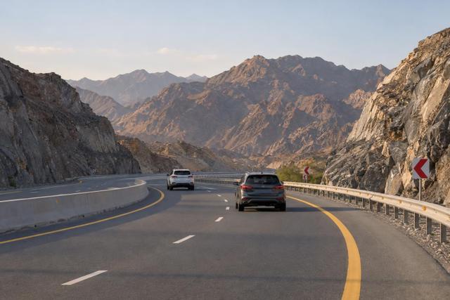 Cars travelling through a guarded bend on the mountainous Fujairah–Khorfakkan route.